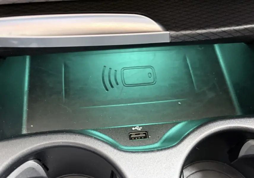 Gros plan sur la console centrale noire de la BMW Série 5 Touring 530e avec chargeur sans fil et port USB visible.
