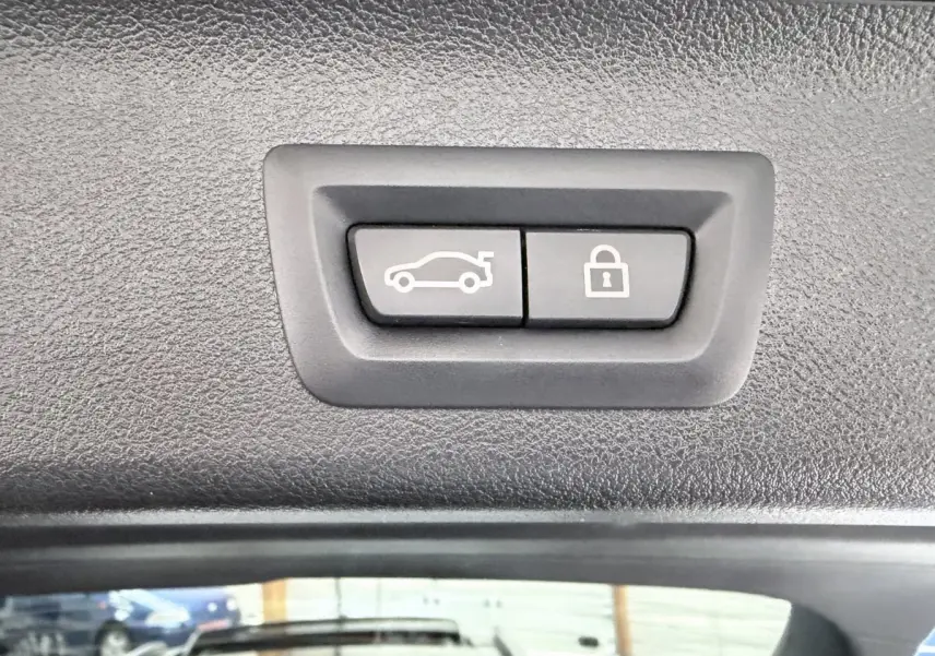 Boutons d'ouverture et de verrouillage du coffre sur le hayon intérieur d'une BMW Série 5 Touring noire 2023.