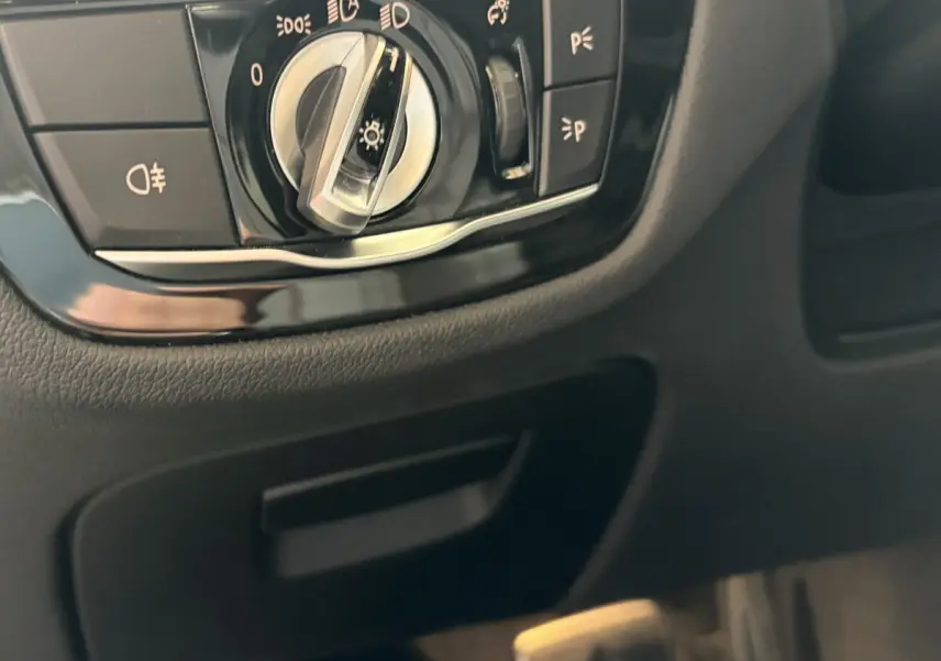 Gros plan sur la commande des phares noire et chromée dans l’habitacle d’une BMW Série 5 Touring 530e noire.