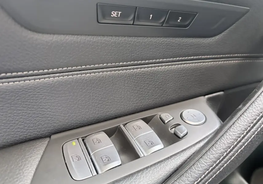 Gros plan sur la commande des vitres côté conducteur en cuir noir de la BMW Série 5 Touring 530e M Sport 2023.