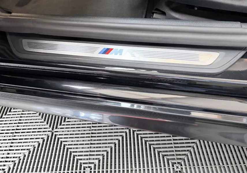 Gros plan sur la plaque de seuil de porte M Sport côté gauche d'une BMW Série 5 Touring noire 2023.