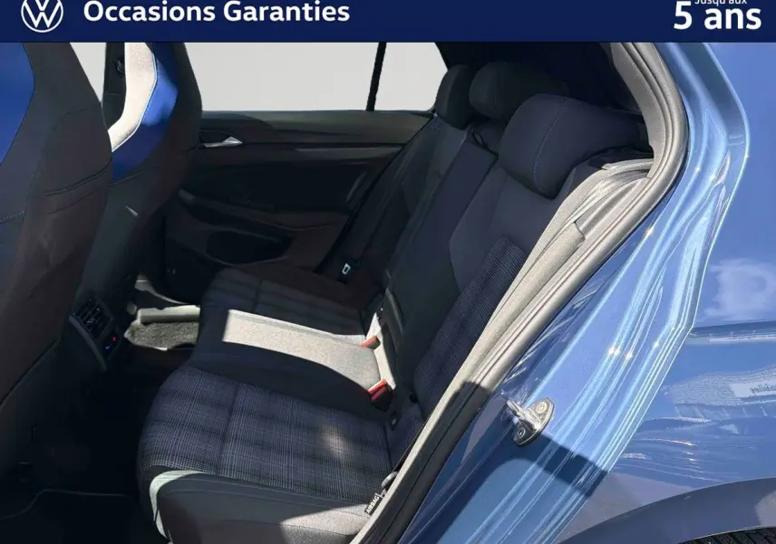 Vue côté arrière droit de l’habitacle bleu d’une Volkswagen Golf 1.5 eHybrid 2025, sièges arrière en tissu à motifs.