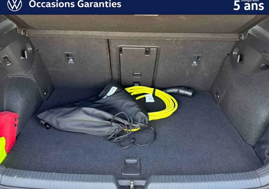 Coffre ouvert d’une Volkswagen Golf 1.5 eHybrid 2025 bleu, montrant un câble de recharge jaune et un sac noir à l’intérieur.