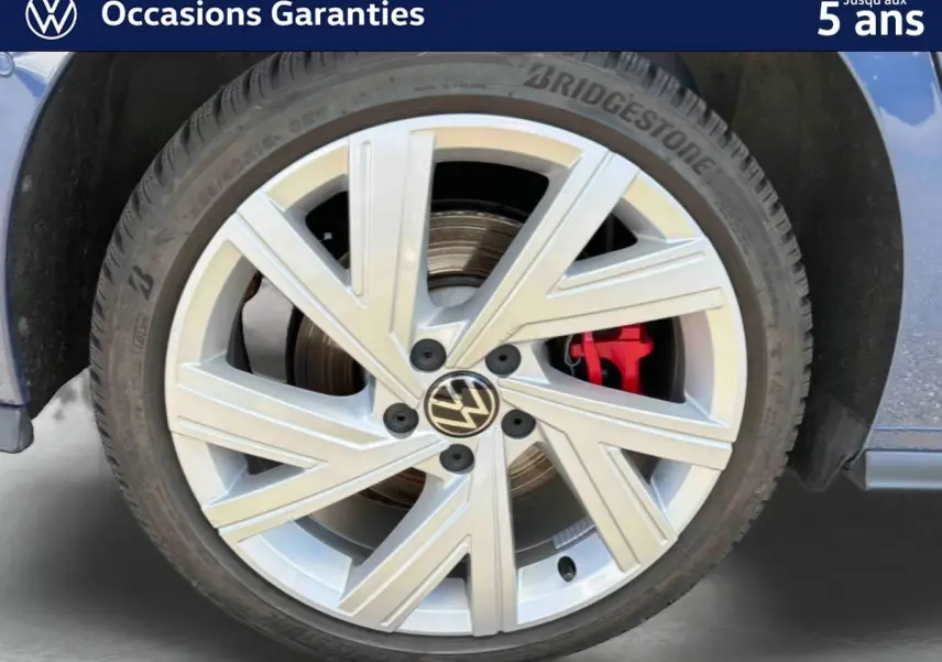 Gros plan sur la jante alliage 17'' Richmond argentée avec étrier de frein rouge d’une Volkswagen Golf 1.5 eHybrid bleue.