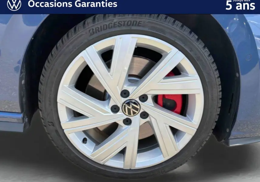 Gros plan sur la roue avant gauche d'une Volkswagen Golf 1.5 eHybrid bleue avec jante alliage 17'' Richmond et étrier de frein rouge.