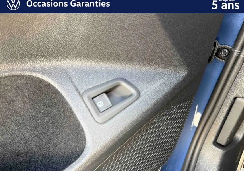 Détail de la porte arrière gauche bleu métallisé de la Volkswagen Golf 1.5 eHybrid 2025 avec commande d’ouverture de trappe à carburant.