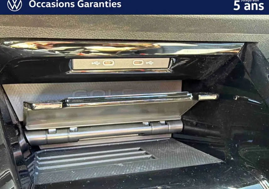 Gros plan sur la console centrale noire brillante de la Volkswagen Golf 1.5 eHybrid 2025 avec deux ports USB-C visibles.