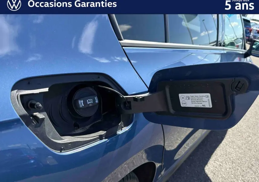 Vue rapprochée de la trappe à carburant ouverte côté gauche d'une Volkswagen Golf 1.5 eHybrid bleue 2025.