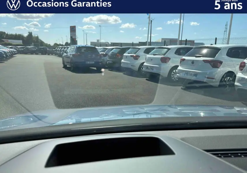 Vue avant depuis l'habitacle d'une Volkswagen Golf bleue 2025 avec affichage tête haute visible sur le pare-brise.
