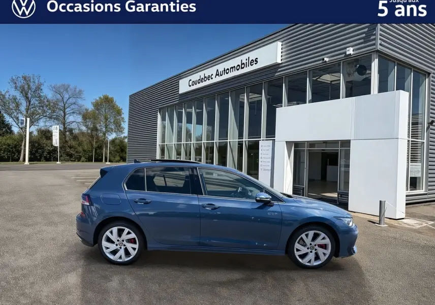 Vue latérale gauche d'une Volkswagen Golf 1.5 eHybrid 272 DSG6 bleue métallisée, avec jantes alliage 17'' et badges GTE visibles.
