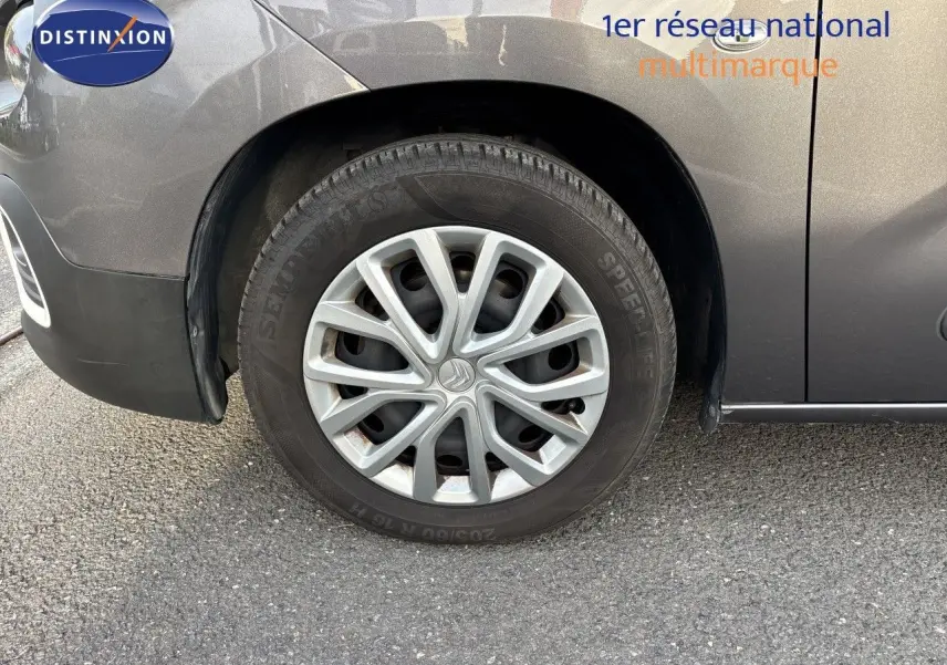 Gros plan sur la roue avant gauche d'une Citroën Berlingo Multispace gris platinium, mettant en valeur la jante et la carrosserie.
