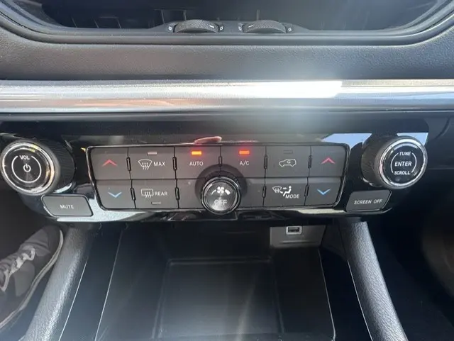 Vue rapprochée de la console centrale noire du Jeep Compass 2025, avec commandes climatisation et boutons lumineux.