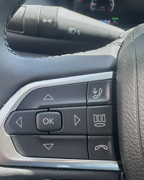 Gros plan sur les commandes multifonctions noires au volant du Jeep Compass 2025, avec boutons de navigation et appels.