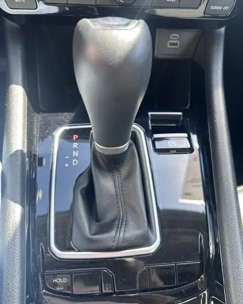 Gros plan sur le levier de vitesses automatique noir de la Jeep Compass 2025 avec bouton frein à main électronique et prises USB.
