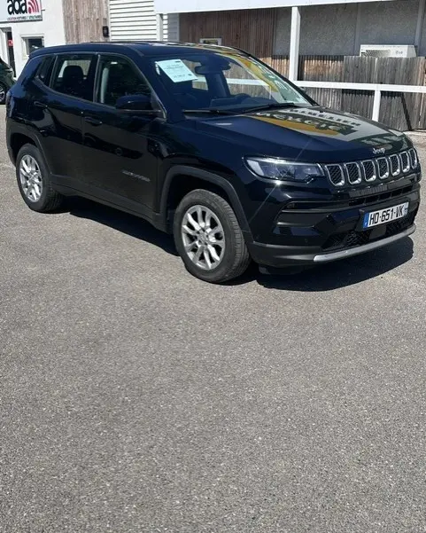 Jeep Compass noir vue 3/4 avant droit, jantes alliage 18 pouces, calandre distinctive à sept fentes, stationné en extérieur.