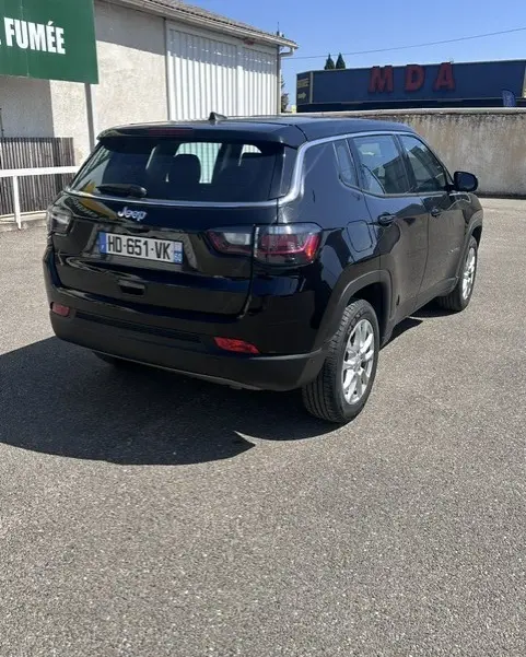 Jeep Compass noir vue 3/4 arrière droit, jantes alliage 18 pouces, stationné en extérieur sous soleil.
