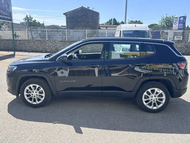 Vue de profil côté gauche d'un Jeep Compass noir 2025 avec jantes alliage 18 pouces sur parking extérieur.