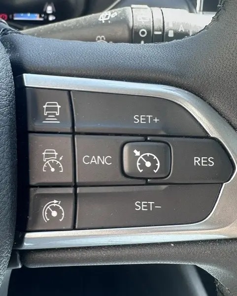Gros plan sur les commandes du régulateur de vitesse au volant du Jeep Compass noir 2025, version e-Hybrid Altitude.