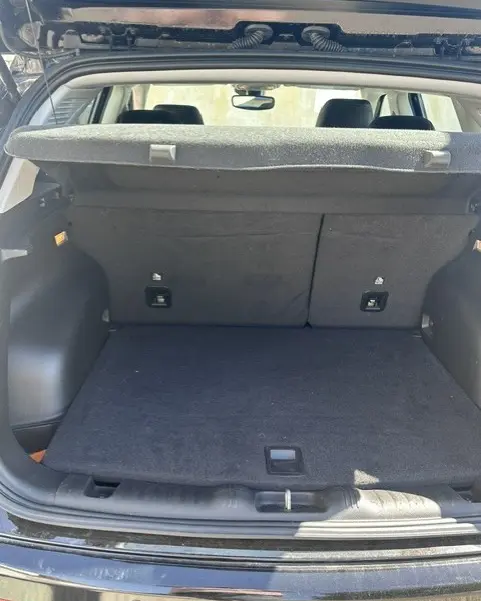 Coffre ouvert vu de l'arrière d'un Jeep Compass noir 2025, montrant un espace de chargement propre avec cache-bagages.
