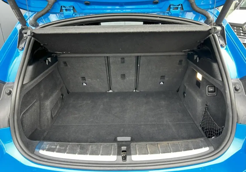 Coffre ouvert vu de l'arrière du BMW X2 bleu Misano, montrant un espace de rangement propre et bien agencé.