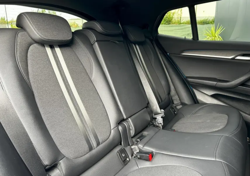 Vue latérale droite de l'intérieur arrière d'une BMW X2 2021 avec sièges noirs en cuir et tissu, finition M Sport.