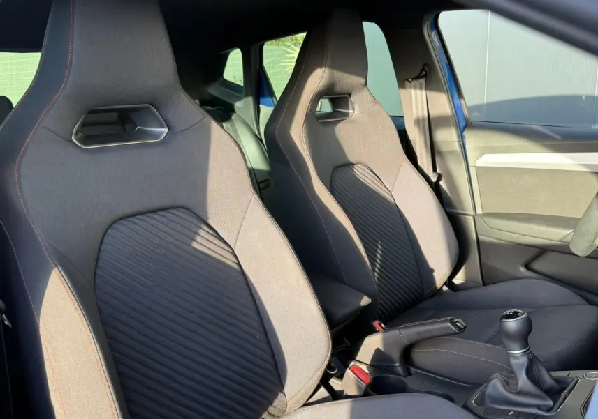 Vue intérieure côté avant droit des sièges sport noirs avec surpiqûres orange et levier de vitesse manuel d'une SEAT IBIZA TSI 115 FR bleu saphir 2025.