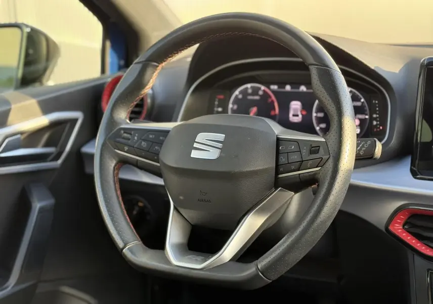 Volant multifonction de la SEAT Ibiza TSI 115 FR 2025, vue rapprochée de l'intérieur côté conducteur avec détails rouges.