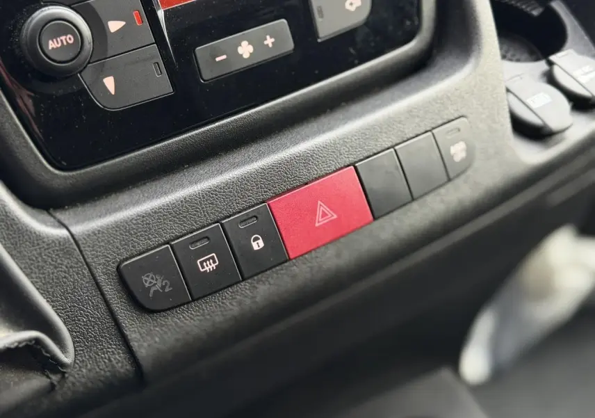 Gros plan sur la console centrale noire de l'Opel Movano Fourgon avec boutons de sécurité et climatisation.