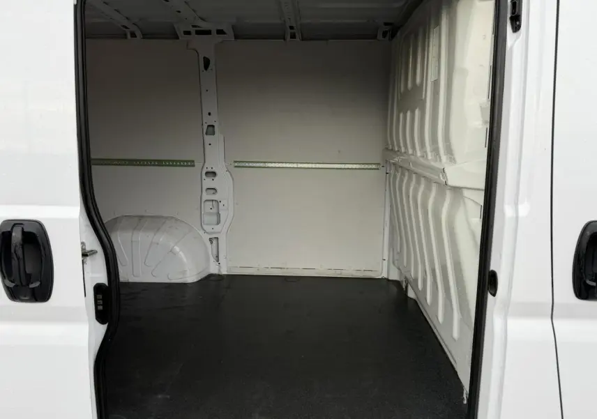 Vue intérieure du fourgon Opel Movano blanc, plancher bois visible avec portes latérales ouvertes.