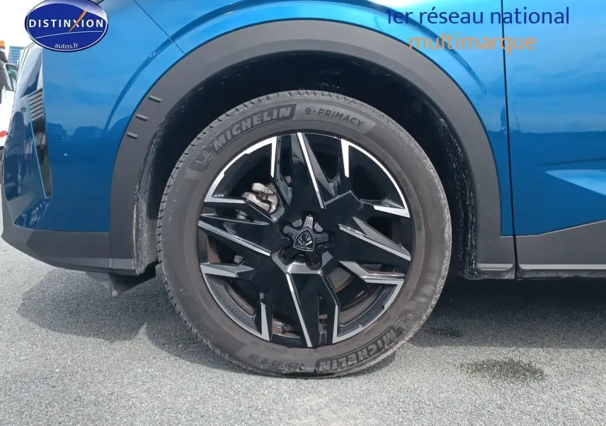 Gros plan sur la roue avant gauche d'un Peugeot 5008 Hybrid 145 allure bleu, jante alu noire et argentée.