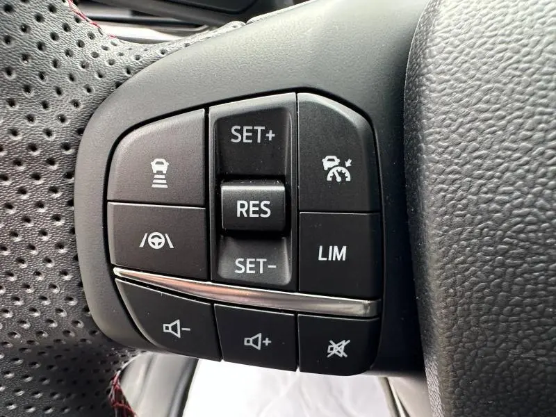 Gros plan sur les commandes noires du volant perforé du Ford Puma 2024, version 1.0 EcoBoost ST-Line.