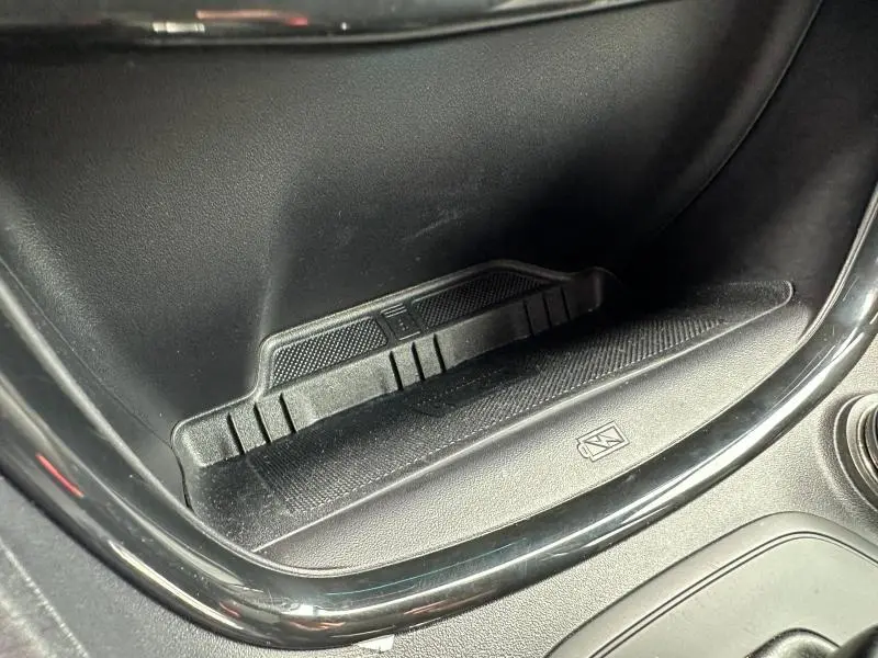 Gros plan sur le rangement intérieur noir mat du Ford Puma 2024, soulignant un espace fonctionnel avec symbole de charge sans fil.