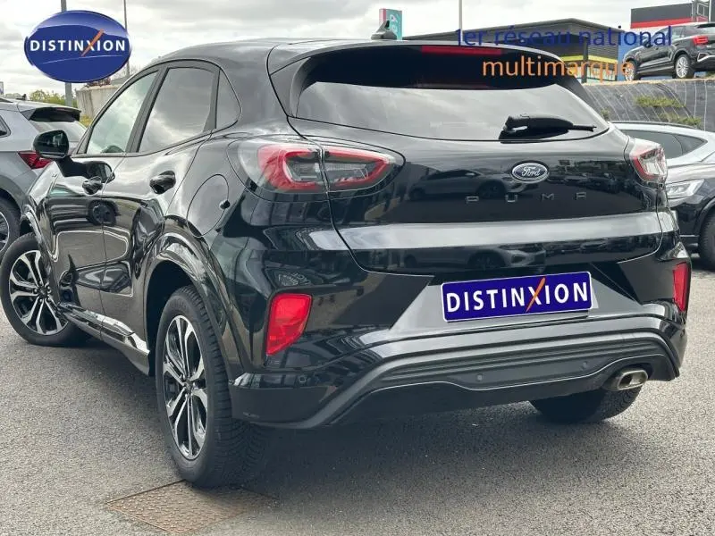 Vue 3/4 arrière droite du Ford Puma 2024 noir Agate métallisé avec feux arrière LED et double sortie d'échappement visible.
