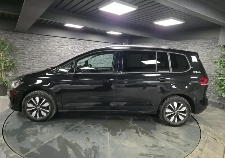 Vue latérale droite d'un Volkswagen Touran noir nacré 2025 avec jantes alliage et badge GOAL à l'arrière.