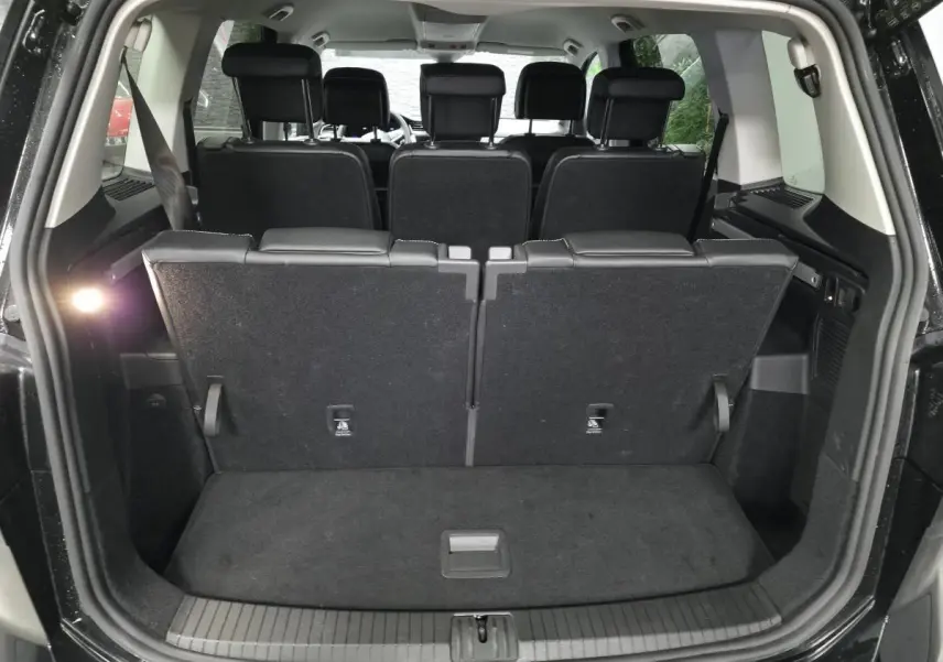 Coffre ouvert vu de l'arrière d'un Volkswagen Touran noir 7 places, sièges arrière en position verticale.