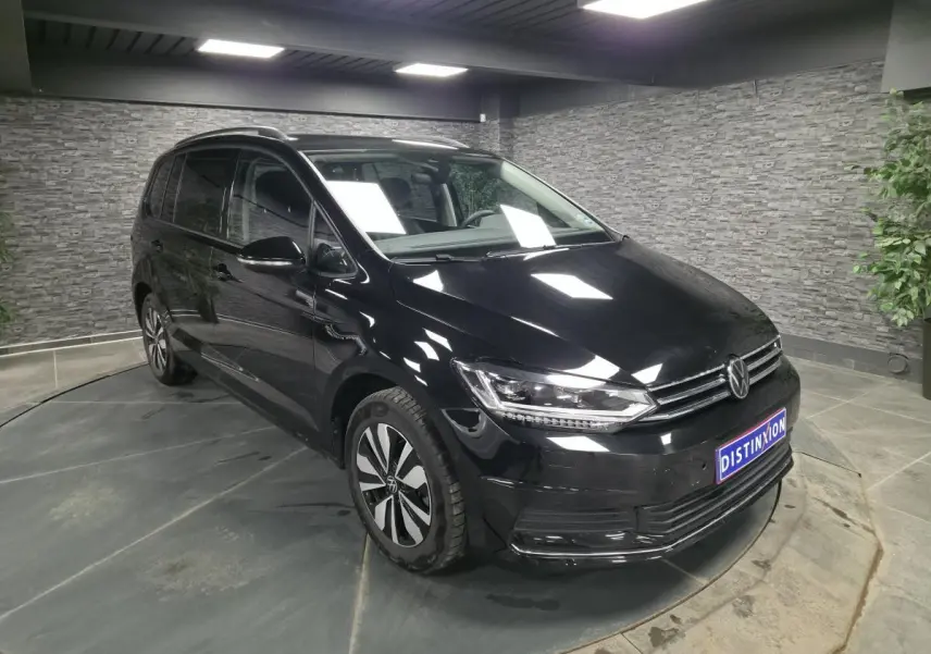 Volkswagen Touran noir en 3/4 avant droit, avec calandre chromée et jantes alliage distinctives.