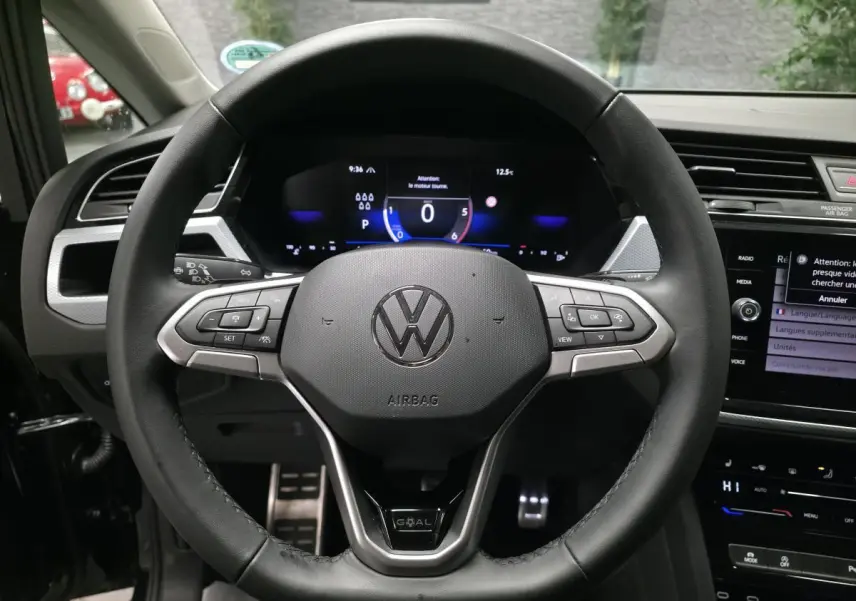 Vue rapprochée du volant cuir multifonction noir du Volkswagen Touran 2025 avec badge GOAL et tableau de bord digital.