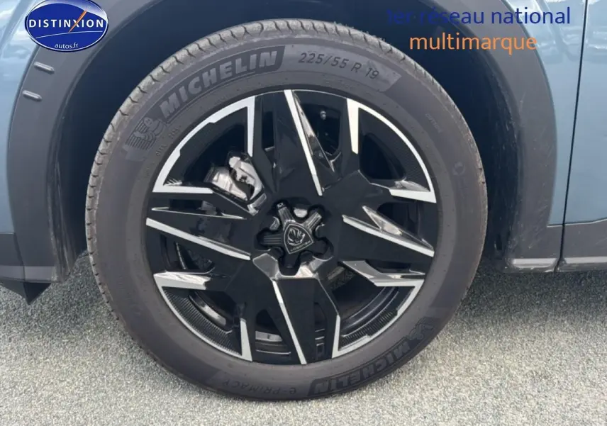 Gros plan sur la roue avant droite avec jante alu noire et argentée du Peugeot 3008 bleu hybride 2025.