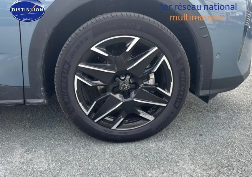 Gros plan sur la roue avant gauche avec jante alu noire et argentée du Peugeot 3008 bleu 2025.