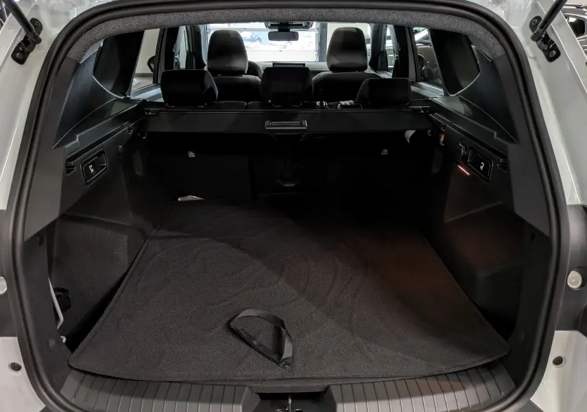 Vue arrière du coffre ouvert du Dacia Bigster blanc Glacier, montrant l'espace de chargement et la banquette arrière noire.