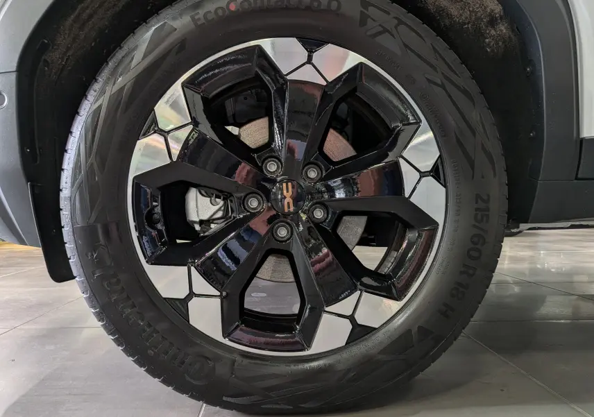 Gros plan sur la roue avant droite du Dacia Bigster blanc Glacier, jante alliage bicolore noire et argentée.