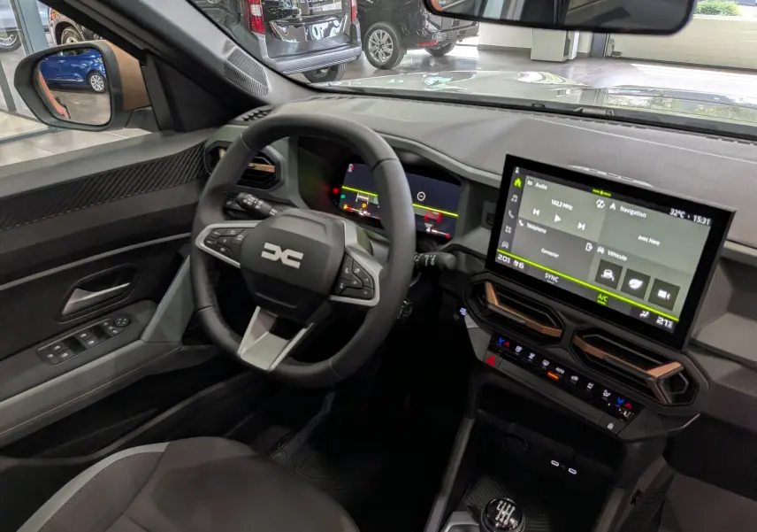 Vue intérieure côté conducteur du Dacia Bigster 2026, tableau de bord moderne avec écran tactile et volant multifonctions noir.