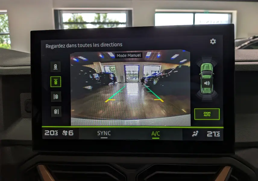 Écran tactile affichant la caméra de recul en mode manuel avec guidage de trajectoire dans un parking intérieur.