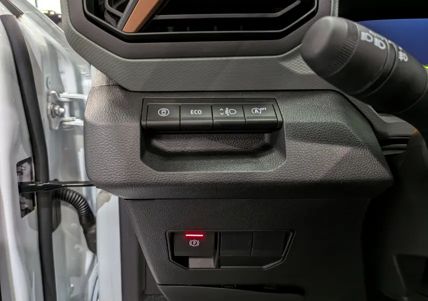 Détail du tableau de bord côté gauche du Dacia Bigster blanc Glacier 2026, avec boutons de contrôle et frein à main électronique.
