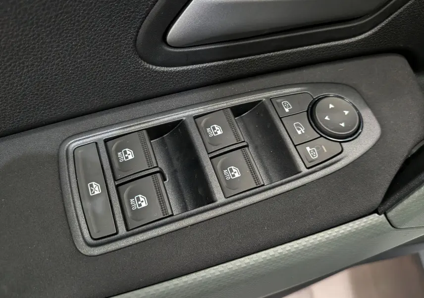 Gros plan sur les commandes des vitres électriques et des rétroviseurs du côté conducteur d'un Dacia Bigster blanc Glacier.