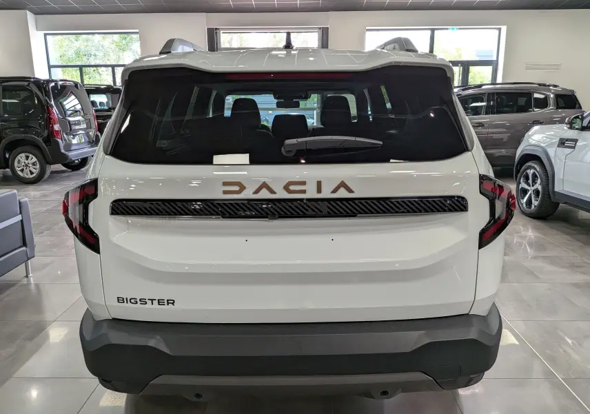 Vue arrière d'un Dacia Bigster blanc Glacier avec logo DACIA en relief cuivré et feux arrière noirs en forme angulaire.