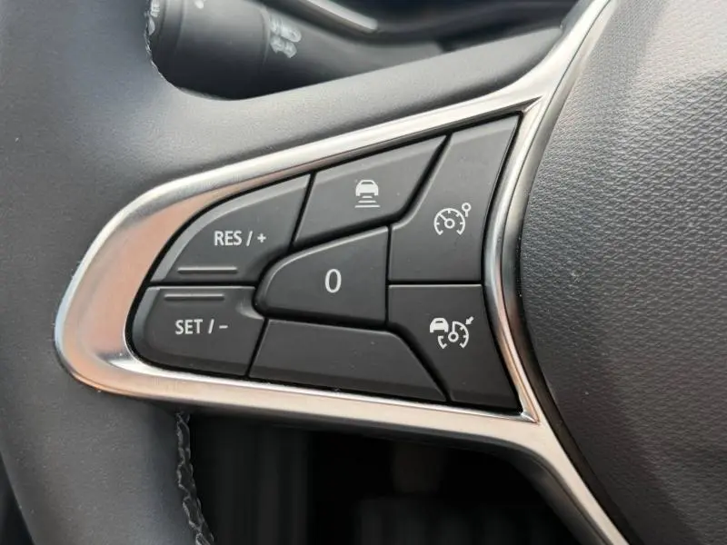 Gros plan sur les commandes multifonctions du volant côté gauche de la Renault Clio gris schiste 2025.