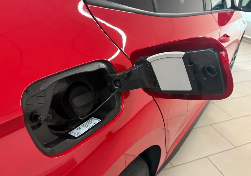 Gros plan sur la trappe à carburant ouverte côté gauche d'une Skoda Fabia rouge Velvet avec toit noir.