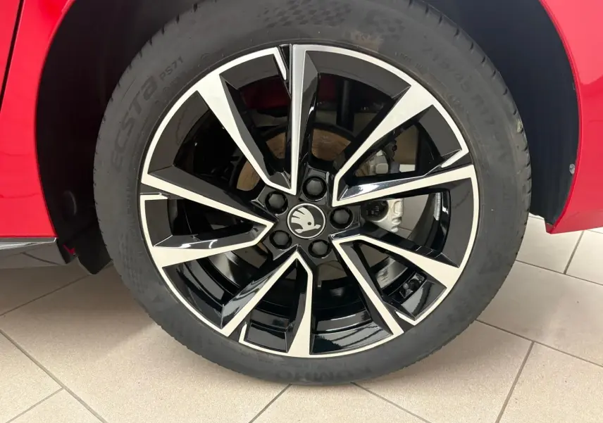Gros plan sur la roue avant droite de la Skoda Fabia rouge Velvet avec jante noire et argentée au design moderne.