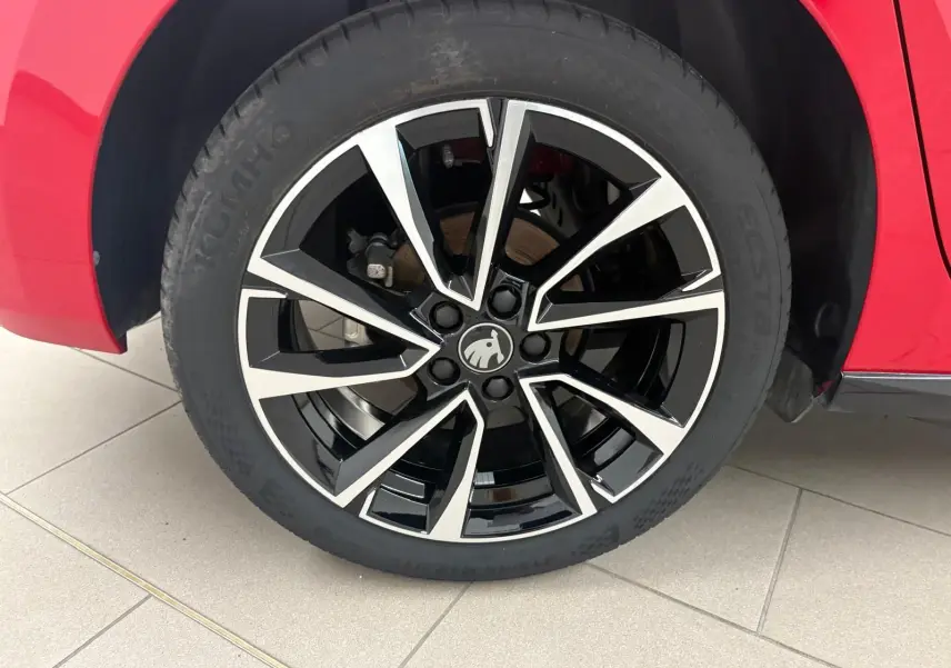 Gros plan sur la roue avant droite d'une Skoda Fabia rouge Velvet avec jante alliage noire et argentée.
